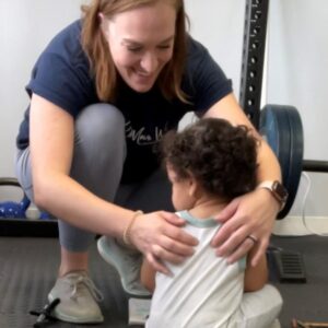 A picture of Dr. Olivia feeling a young kid's back.